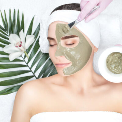 The procedure for applying a mask from clay to the face of a beautiful woman. Spa treatments and care of the face in the beauty salon.