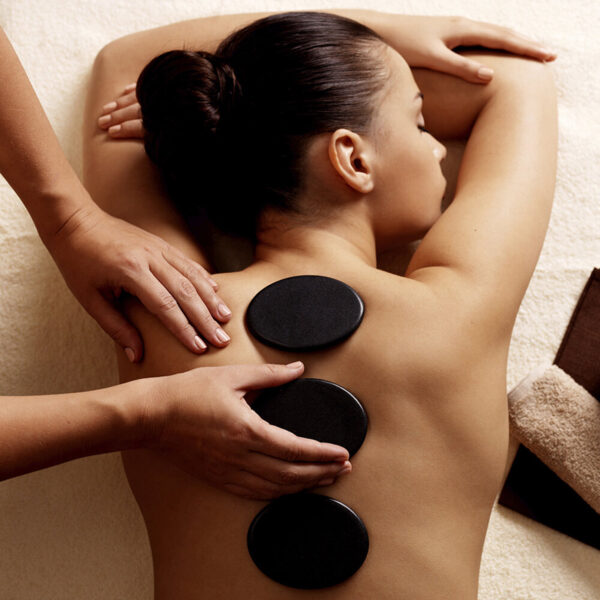 Young woman getting hot stone massage in spa salon. Beauty treatment concept.